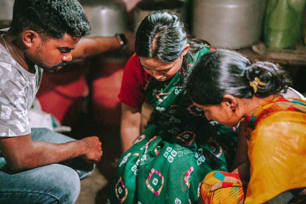 Three Indian Christians praying together indoors during a reenacted prayer time.